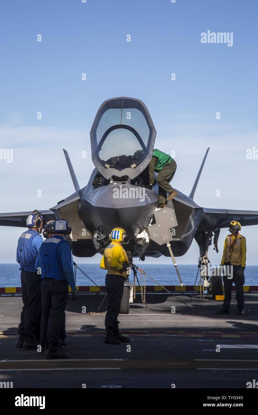 OCEAN (Nov. 7, 2016) Flight deck personnel coordinate with an aircraft launch and recovery crewman as he climbs down from an F-35B Lightning II aircraft before activating the elevator and lowering the aircraft to the hangar bay. U.S. Navy personnel assigned to the amphibious assault ship USS America (LHA 6) have gained valuable hands-on experience with the Short Takeoff and Vertical Landing (STOVL) aircraft during its third and final developmental test phase (DT-III). Stock Photo