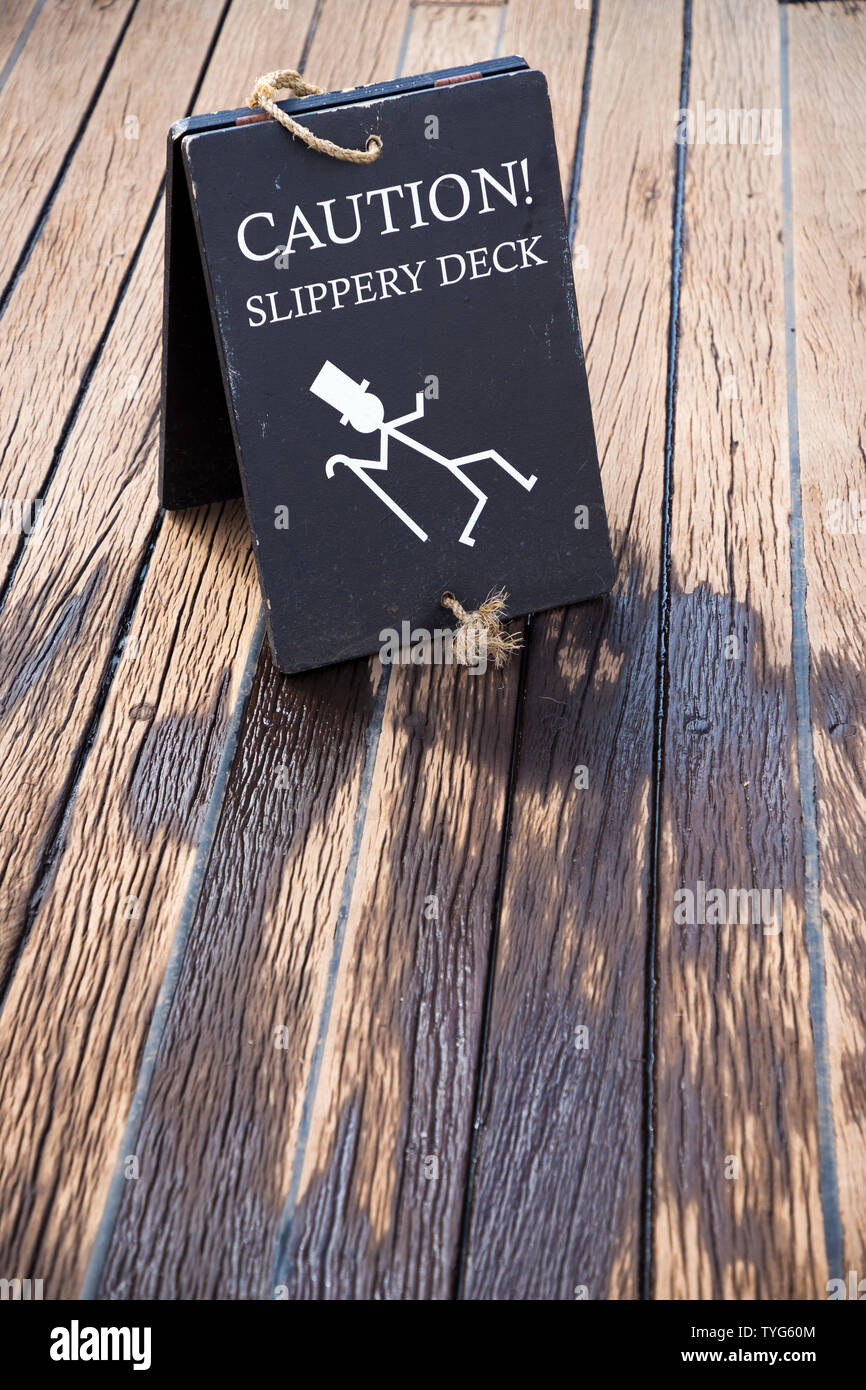 Warning Safety Sign On The Wet Slippery Wooden Weather Deck Of The