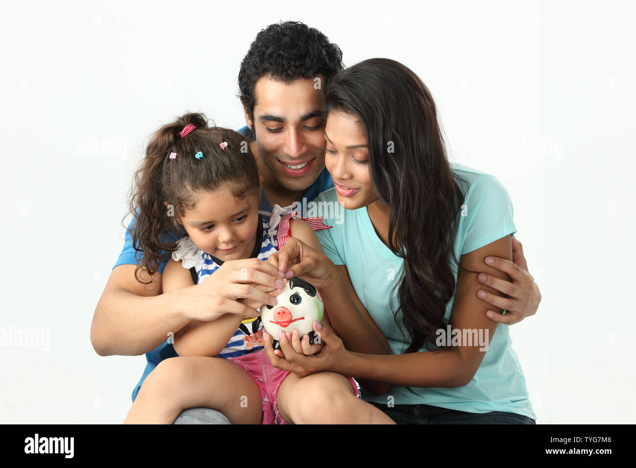 Girl putting coin into a piggy bank with her parents Stock Photo - Alamy