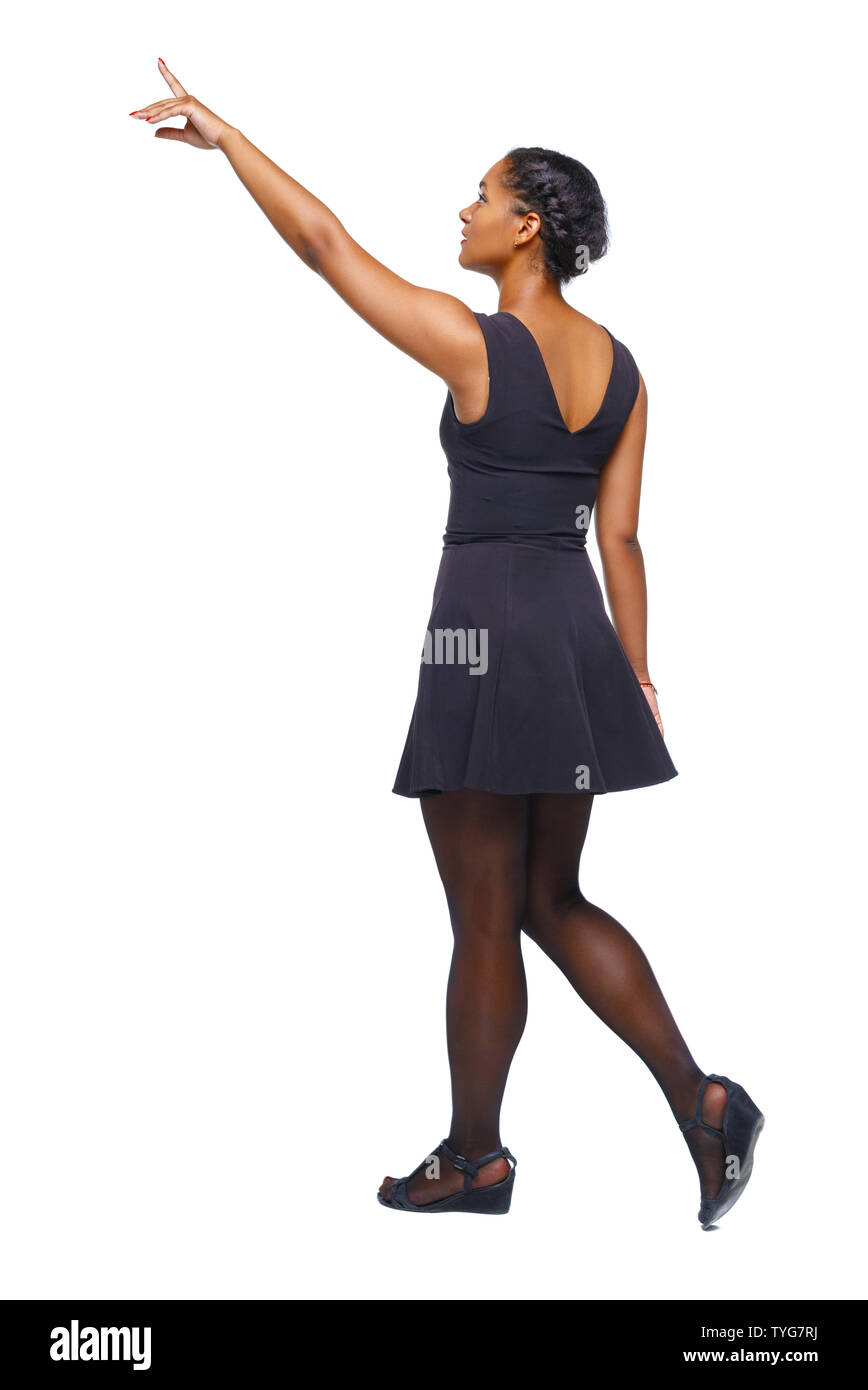 Back view of walking young black girl. going girl showing. backside view of person. Tanned girl in a short dress goes showing a finger to the sky. Rea Stock Photo