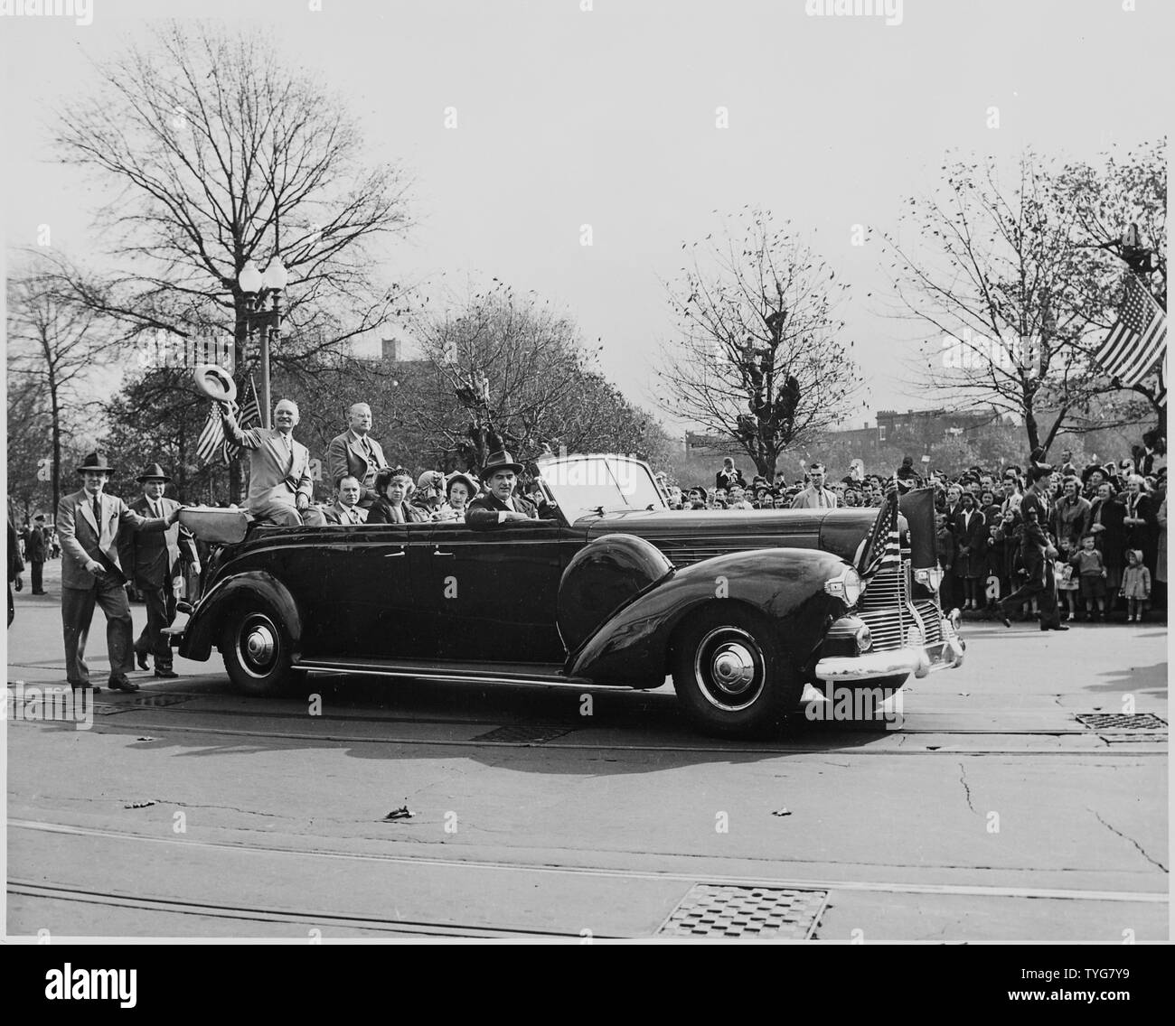 President Harry S. Truman and Vice President-elect Alben W. Barkley, riding on the back of an open car down a street in Washington, DC; President Truman is waving his hat to the crowd. Truman and Barkley had just returned to Washington after winning the election of 1948. Stock Photo