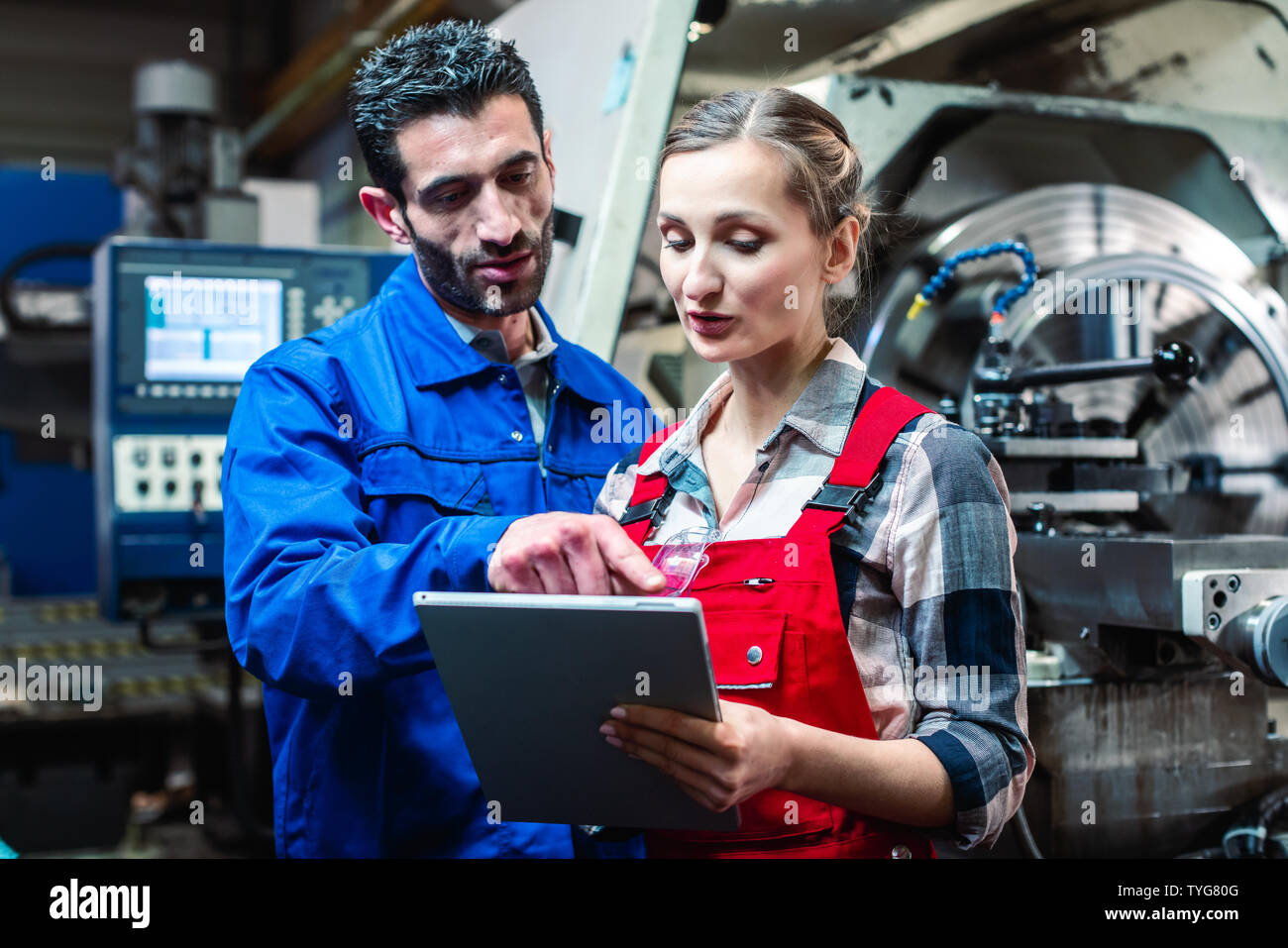 Woman and man manufacturing worker in discussion  Stock Photo