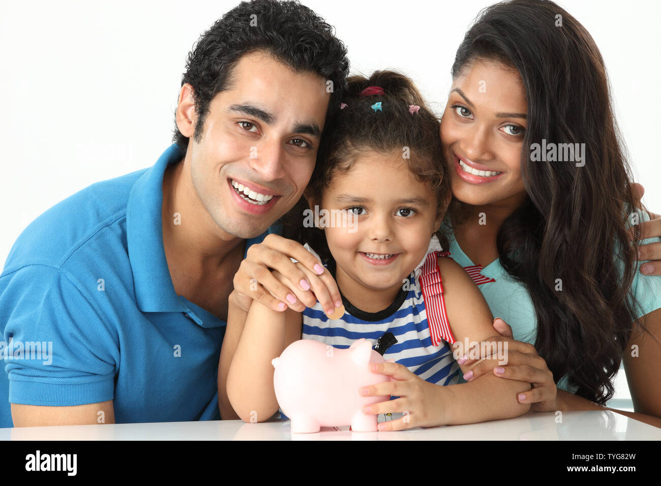 Indian girl putting coin into a piggy bank with her parents Stock Photo ...