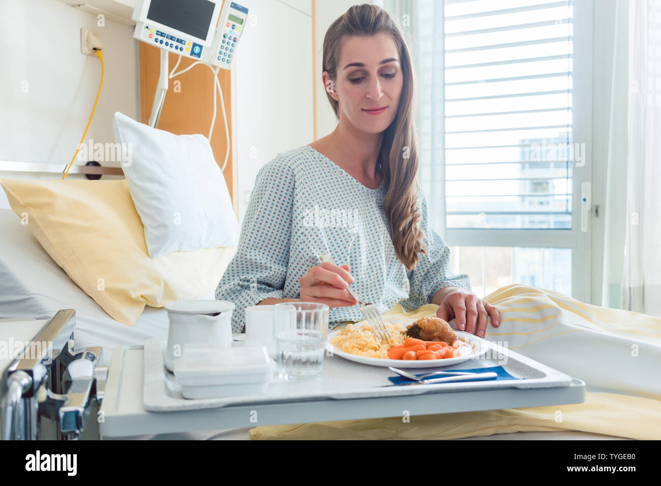 Patient in hospital lying in bed eating meal Stock Photo