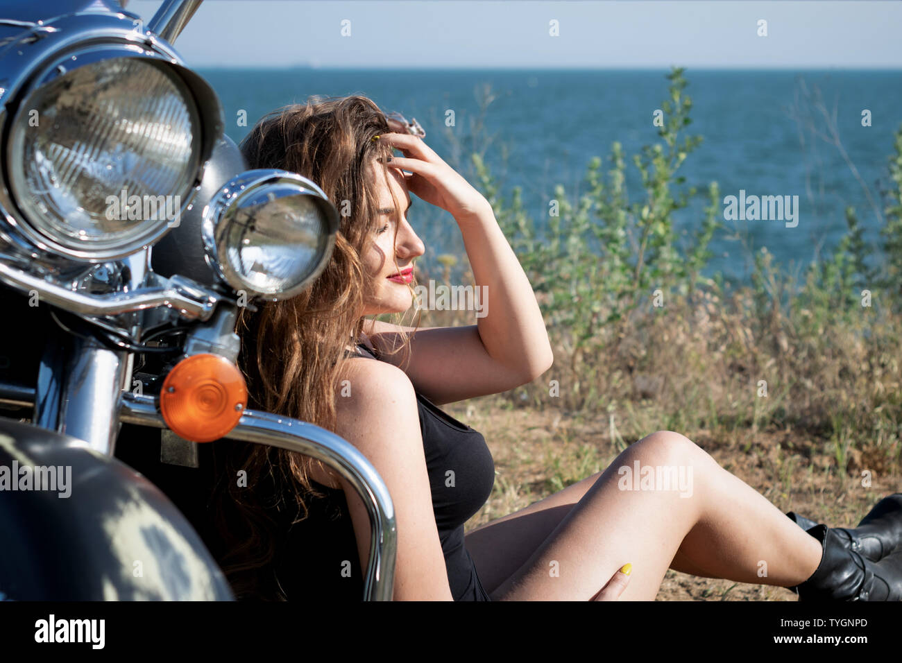 Moto lady in shorts and leather boots sitting near motorbike. biker girl  Stock Photo - Alamy