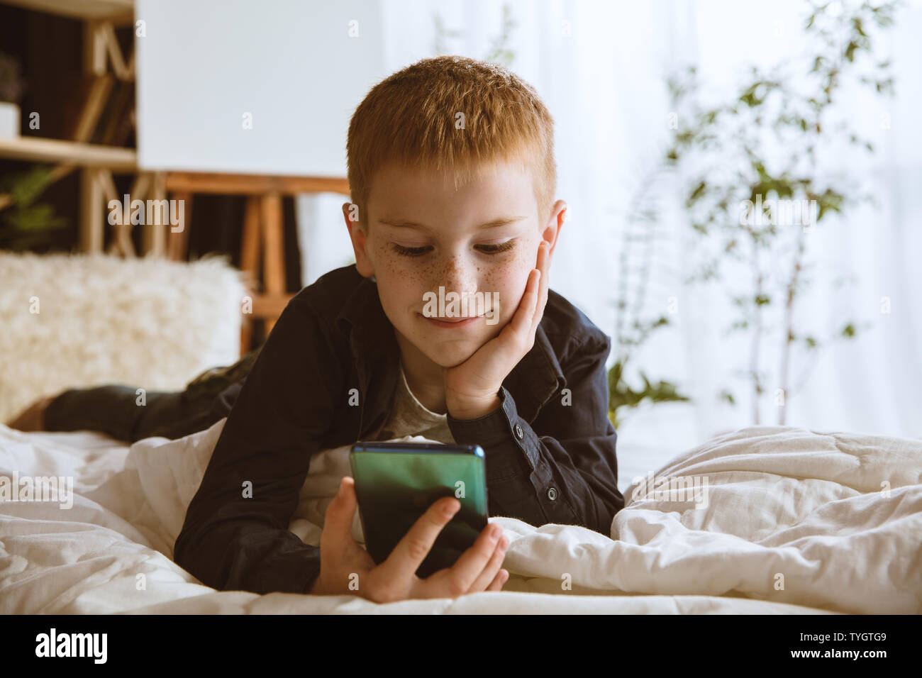 Boy using different gadgets at home. Little model with smart watches ...