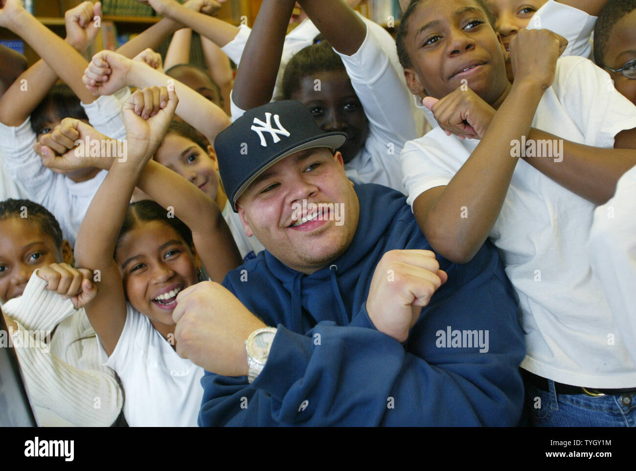 Joseph Cartegena, known as hip-hop artist Fat Joe, poses with students at PS 146 where he has donated 20 new computers to the Bronx school, which he attended as a child, on December 21, 2004 in New York City.  (UPI Photo/Monika Graff) Stock Photo