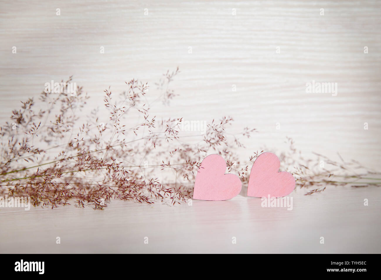 Two hearts, background for greetings on Valentine's Day. Wooden hearts and herbs on a beautiful background. Pink hearts. Stock Photo