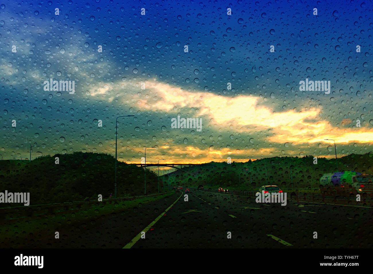 M62 motorway traffic approaching Scammonden Bridge at dusk with rain drops on the windscreen Stock Photo