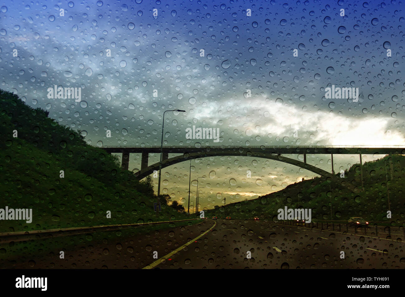 M62 motorway traffic approaching Scammonden Bridge at dusk with rain drops on the windscreen Stock Photo