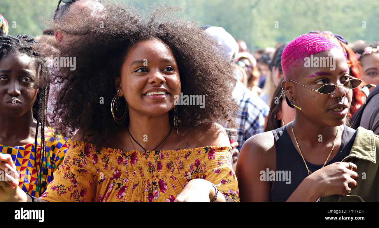 Two black girls one with an afro the other with dyed cropped hair enjoy the music at the 2019 Africa Oye Music Festival in Liverpool’s Sefton Park. Stock Photo