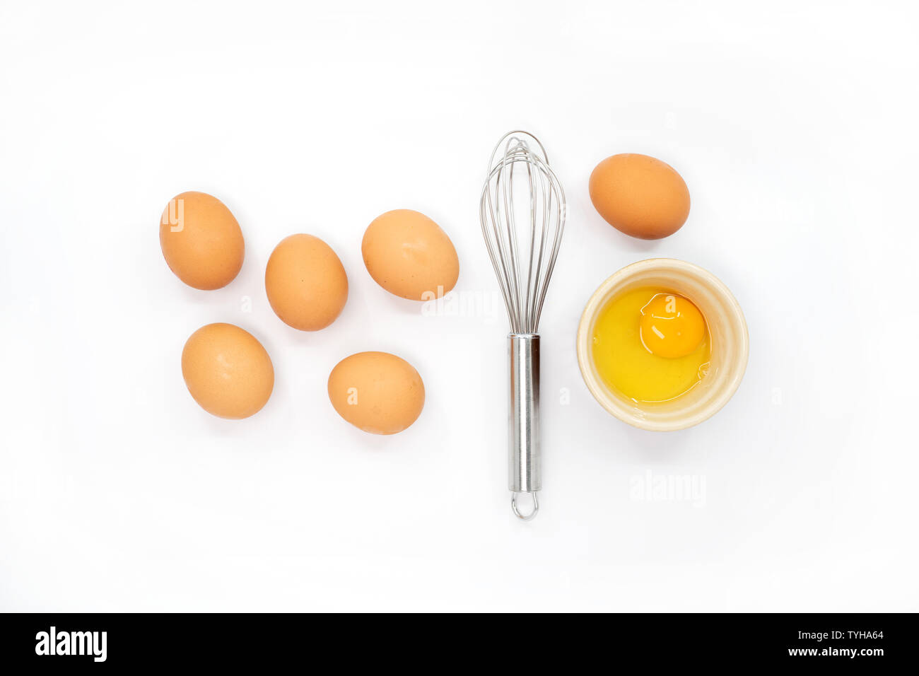 Eggs, a whisk and one egg yolk on a white background Stock Photo