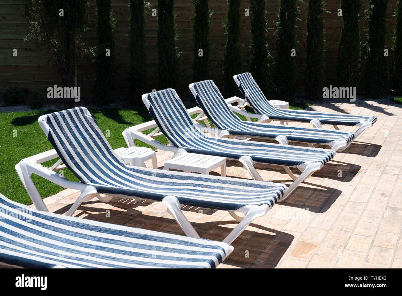 row of stripy blue and white sunbeds in the sun Stock Photo