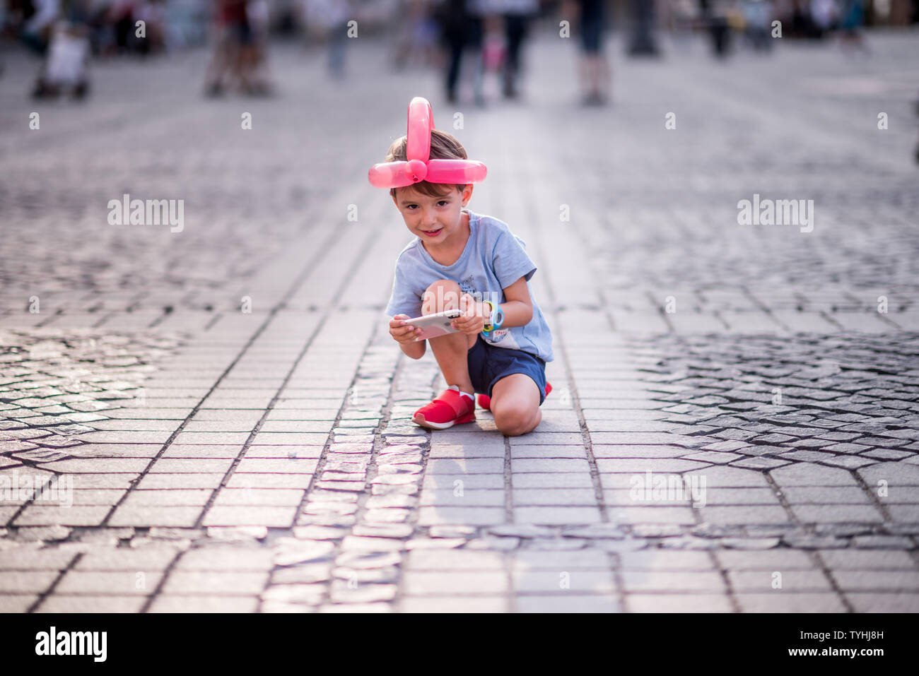 He is the boy with the most daring ideas, such as putting a balloon of various shapes on his head and sitting in a knee on the street. This is his fun Stock Photo