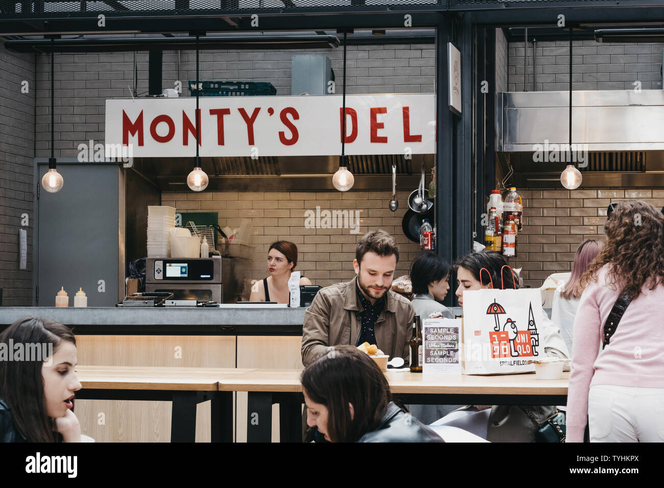 London, UK - June 15, 2019: People enjoying in front of Montys NYC style deli stand at Spitalfields Market, one of the finest Market Halls in London w Stock Photo