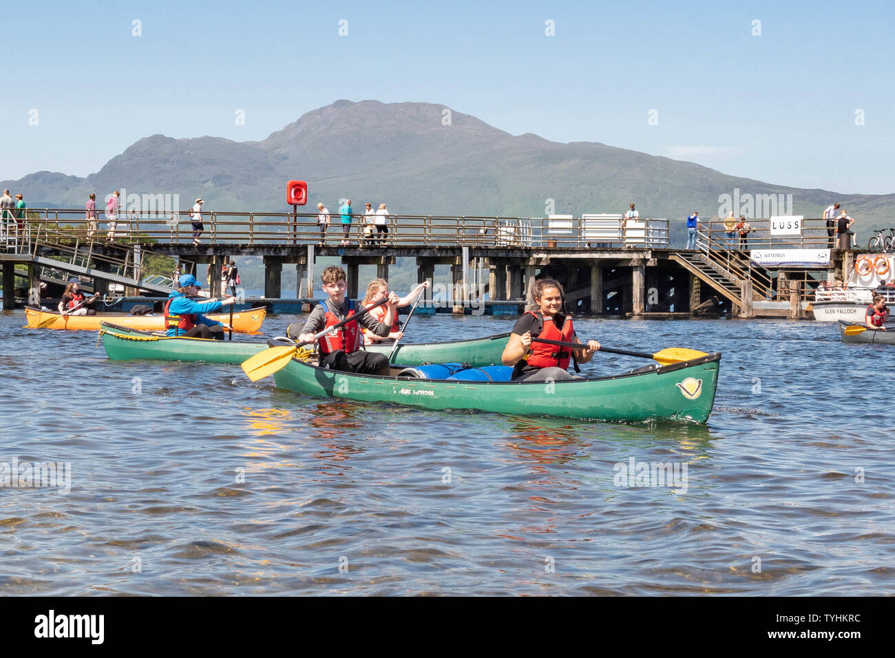 Luss, Loch Lomond, Scotland, UK. 26th June, 2019. UK weather - students from Hillpark Secondary School in Glasgow enjoying brilliant blue skies and bright sunshine this afternoon as they leave the village of Luss paddling on Loch Lomond for their Duke of Edinburgh silver expedition. Credit: Kay Roxby/Alamy Live News Stock Photo