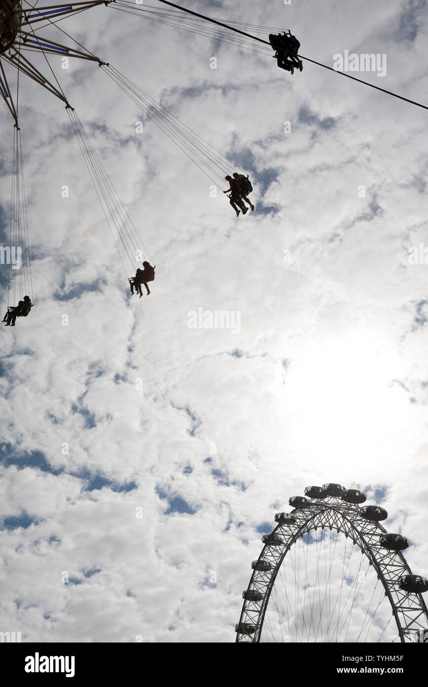 Passengers on a swing ride or chair swing ride with the London Eye in ...