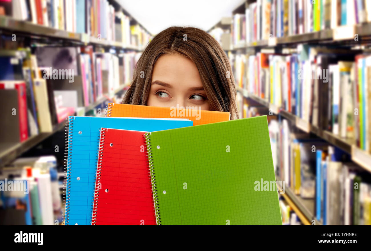 teenage student girl behind notebooks at library Stock Photo - Alamy