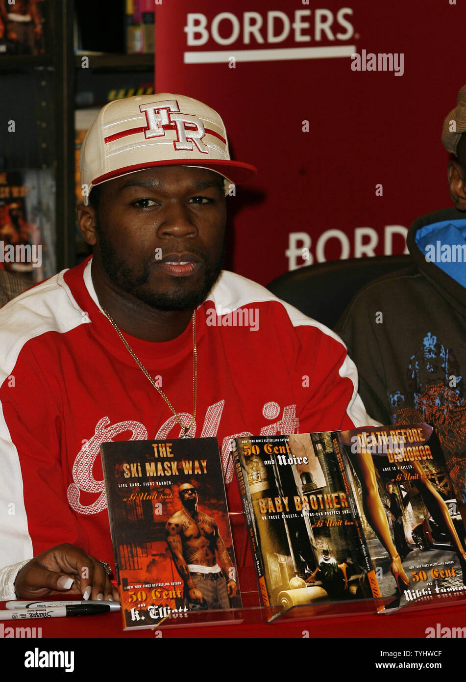 50 Cent sits before copies of 