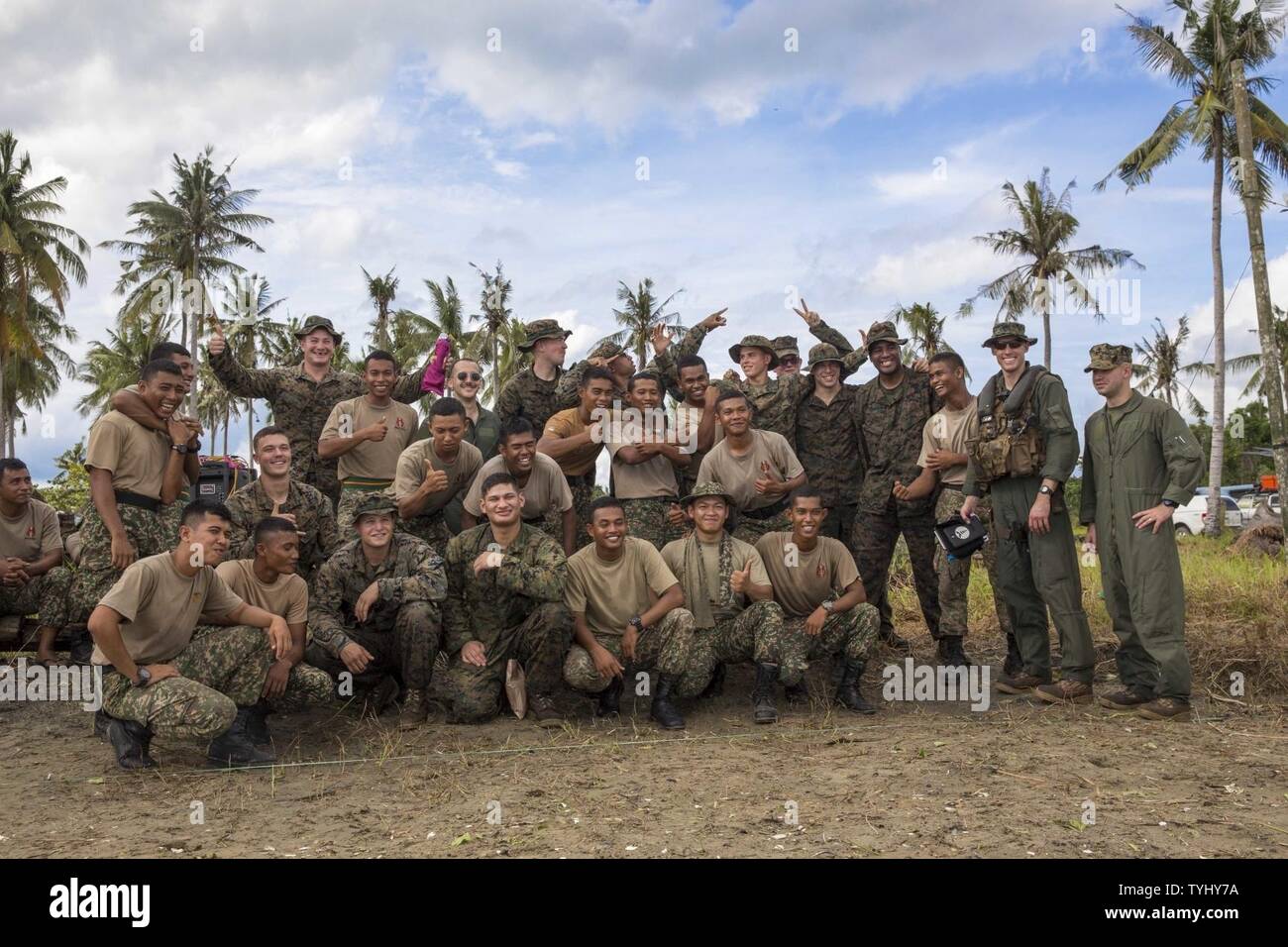 SABAH PROVINCE, Malaysia (Nov. 11, 2016) U.S. Marines and Malaysian Soldiers pose for a picture at the end of the training day in the Sabah Province, Malaysia, during Exercise Tiger Strike 2016, Nov. 11. During Tiger Strike 16, Marines with the 11th Marine Expeditionary Unit conducted partnered training with the 7th Battalion, Royal Malay Regiment, that included jungle survival, combat rubber raiding craft usage, non-lethal weapons, Marine Corps Martial Arts Program, helicopter loading and offloading drills, landing zone security/control, combat service support, and an amphibious assault. Stock Photo