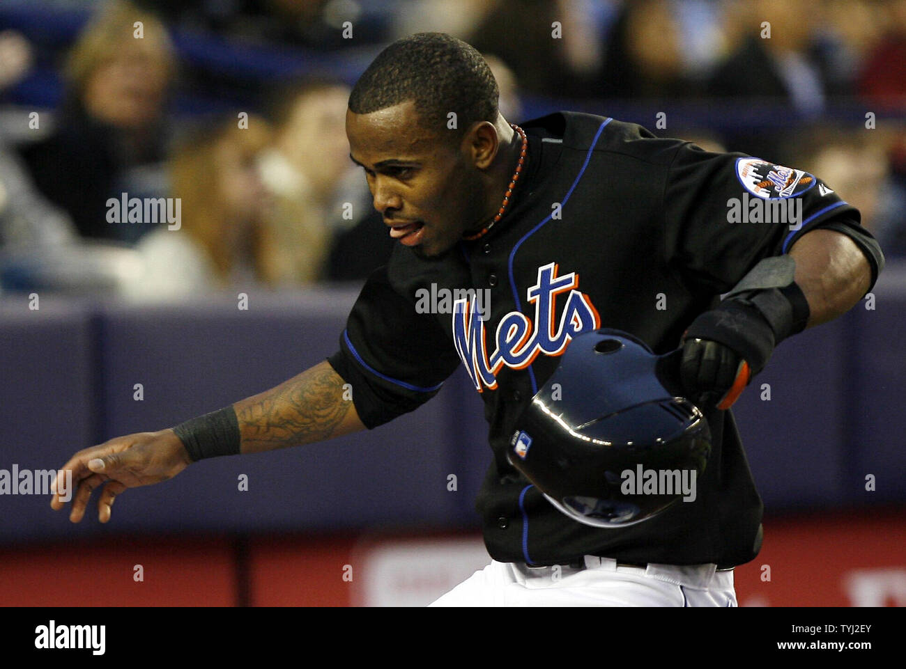 New York Mets Jose Reyes takes off his helmet and runs into the dug out  after scoring on a sacrifice fly against the New York Yankees in the first  inning at Shea