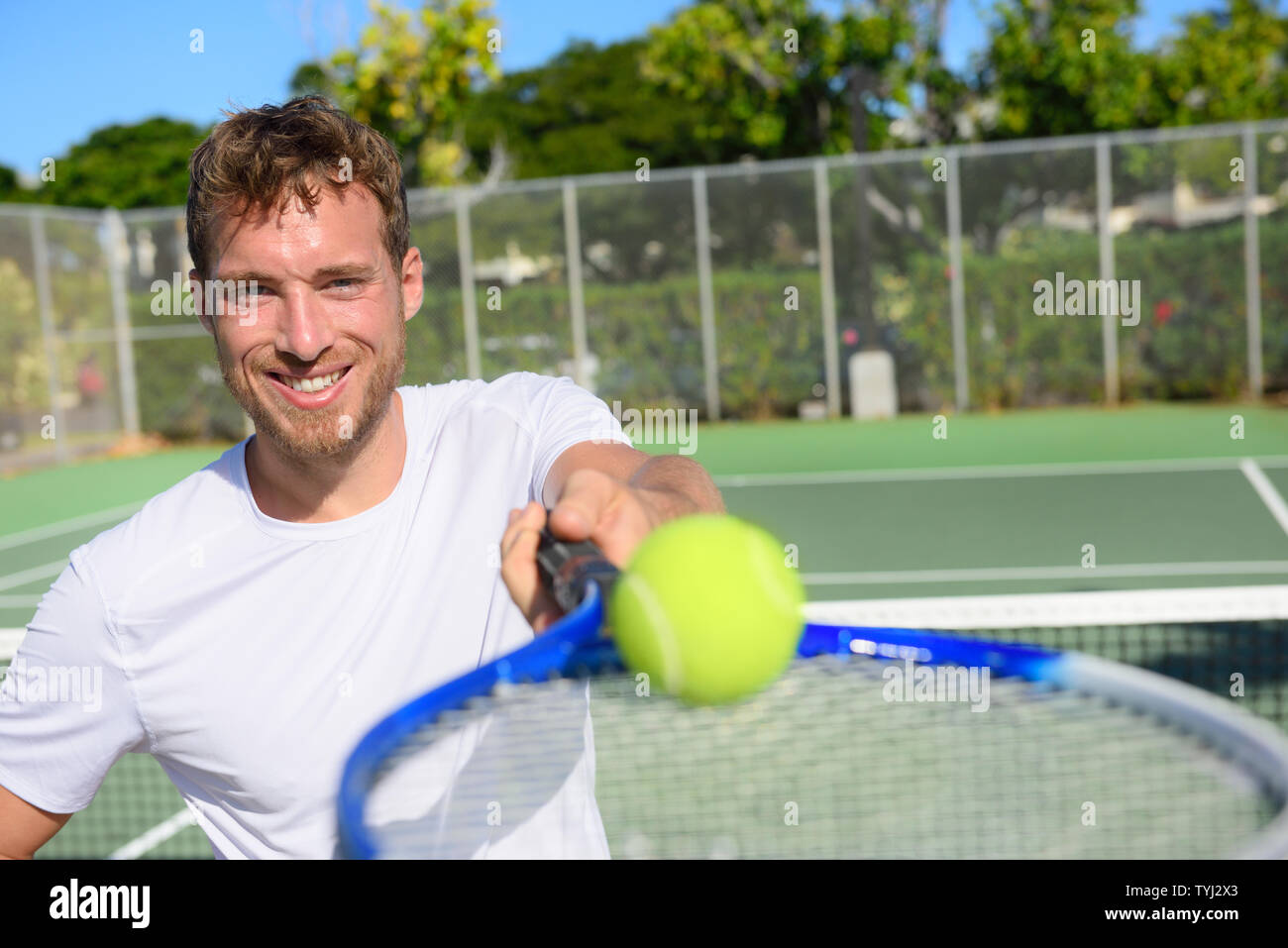 Tennis player portrait man showing ball and racket. Smiling happy male athlete inviting you to play tennis. Healthy active sport and fitness lifestyle concept. Stock Photo