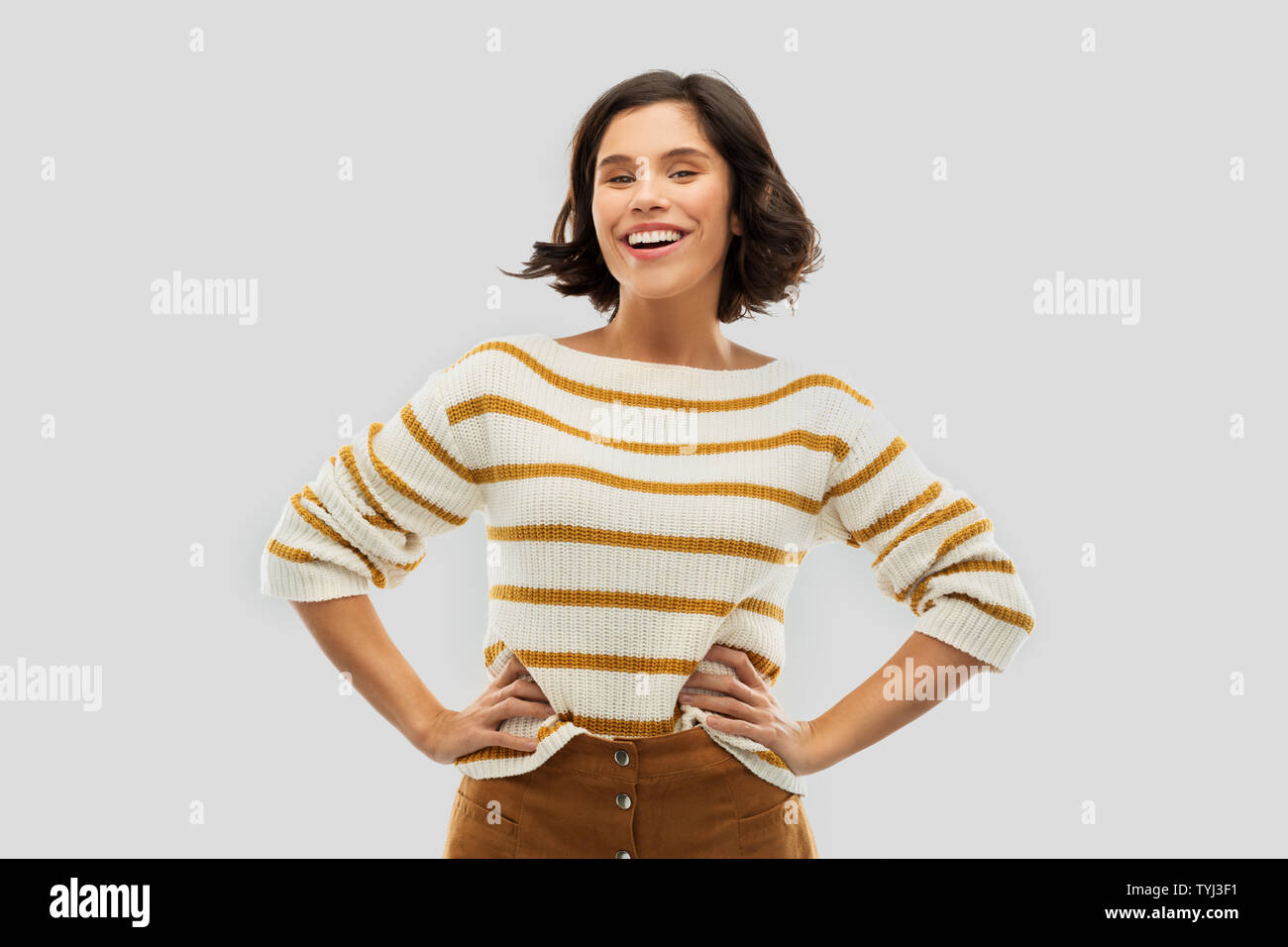 smiling woman in pullover with hands on hips Stock Photo