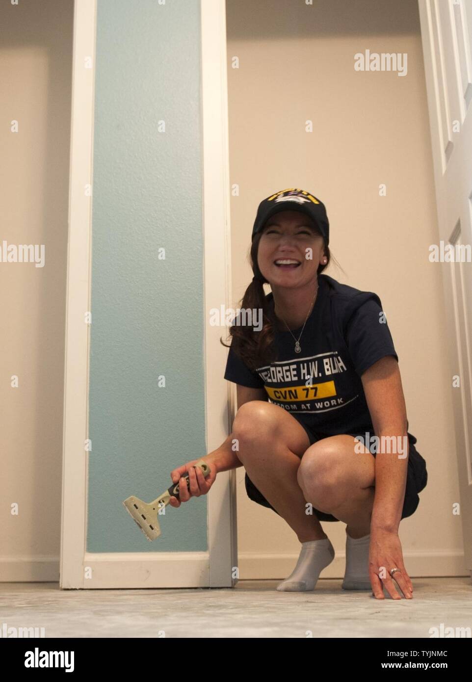(COLLEGE STATION, Texas) Petty Officer 1st Class Joanna Waugh, 2016 Senior Sailor of the Year for the aircraft carrier USS George H.W. Bush (CVN 77), scrapes the foundation of a home during a Habitat for Humanity project in College Station, Texas. The project is part of a two-day namesake trip to Texas where Sailors engaged with the local community about the importance of the Navy. Stock Photo
