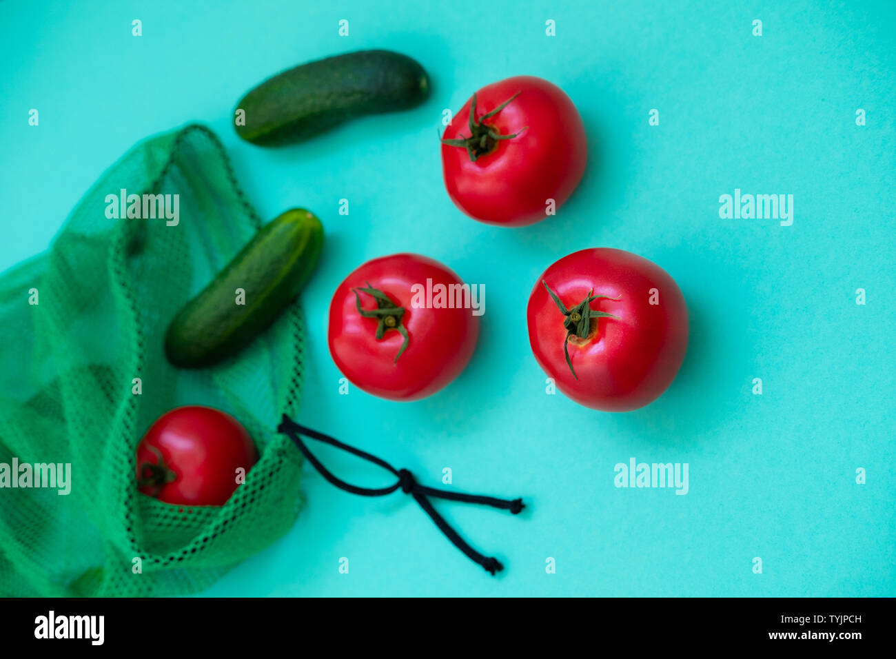 Fresh cucumbers and tomatoes falling out of shopping net. Ripe
