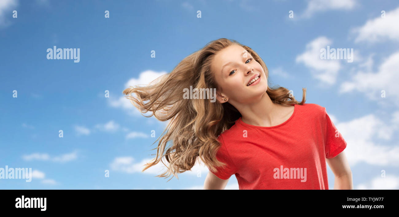 smiling teenage girl in red with long wavy hair Stock Photo