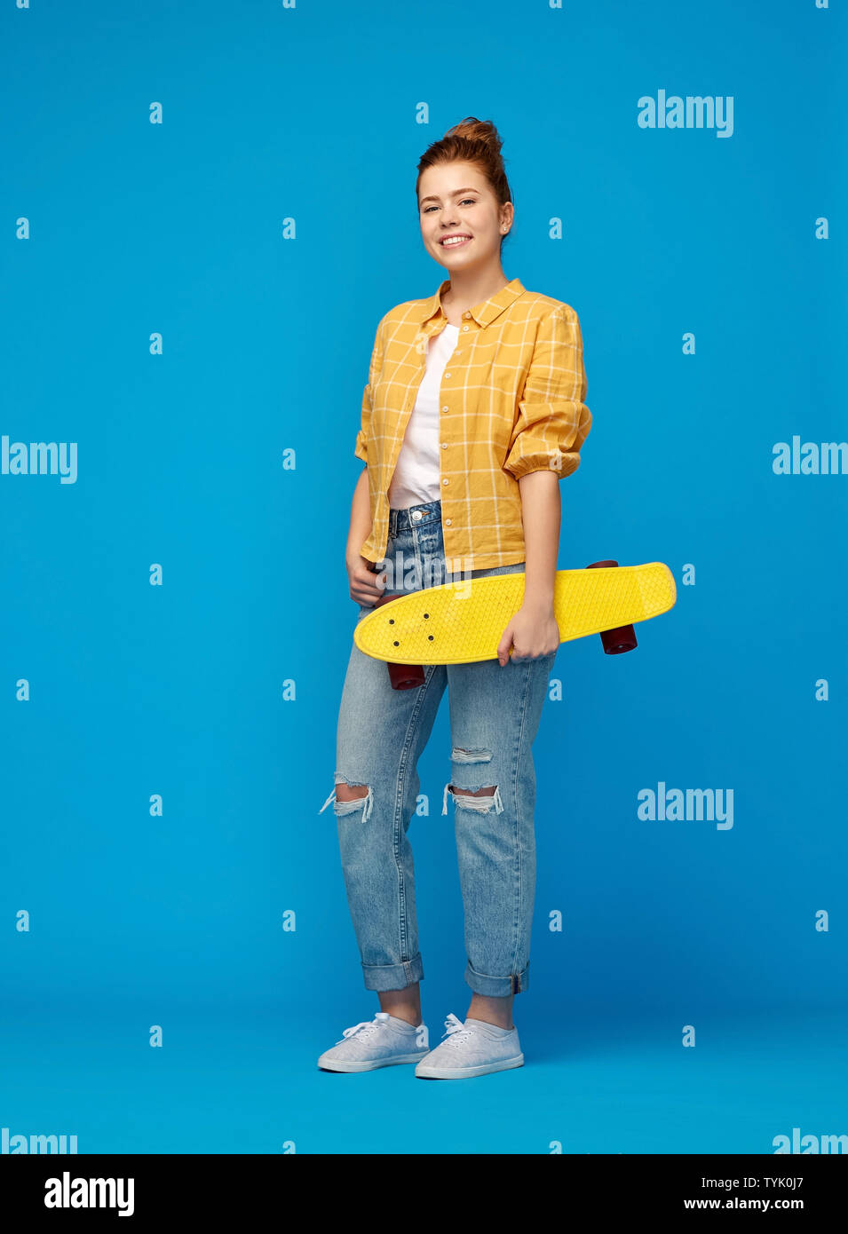 red haired teenage girl with short skateboard Stock Photo