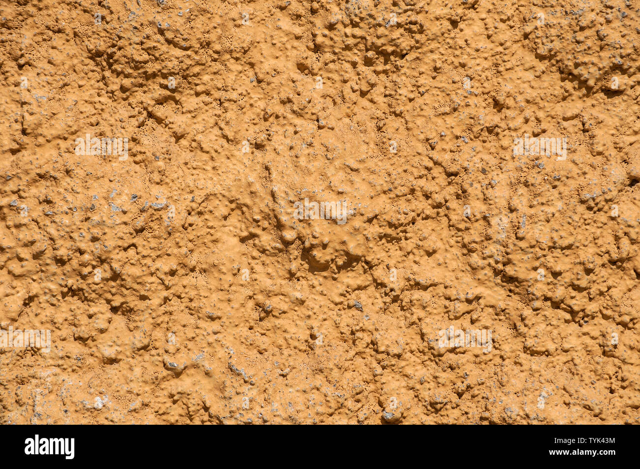 Old vintage grunge ocher painted rough plastered house facade wall closeup as background Stock Photo