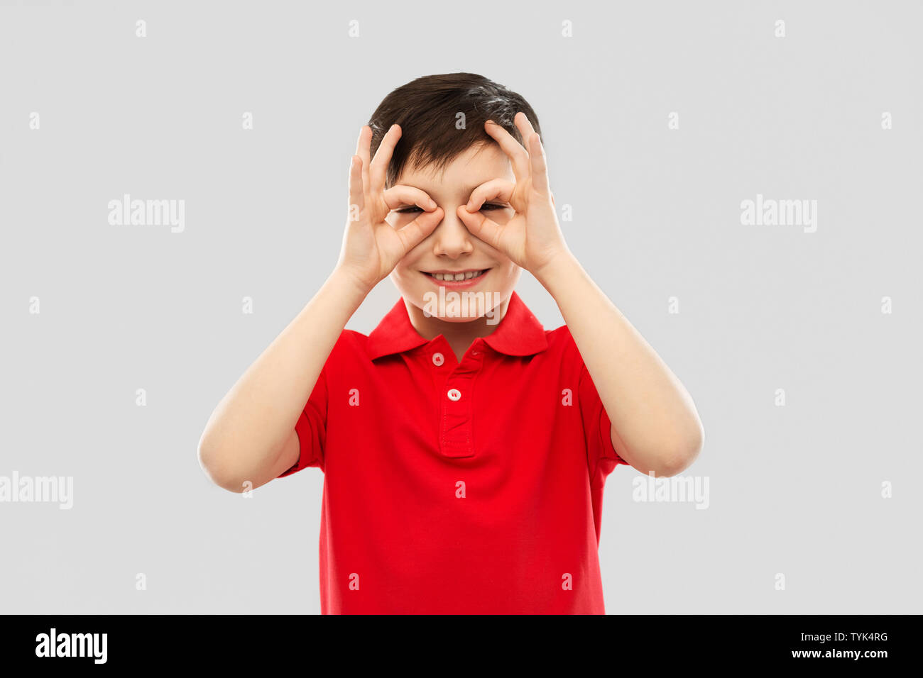 boy in red t-shirt looking through finger glasses Stock Photo