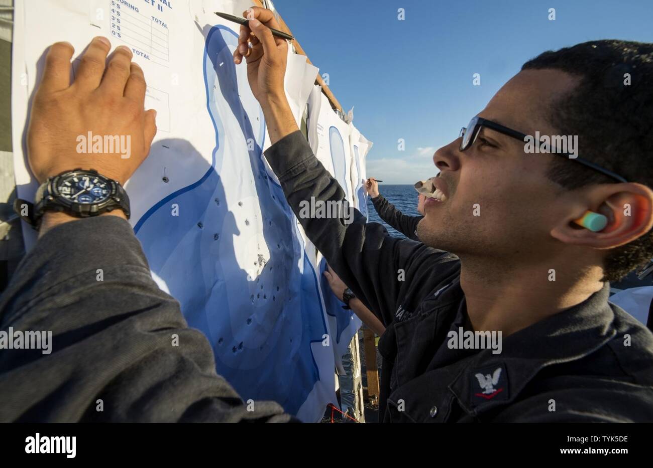 PACIFIC OCEAN (Nov. 13, 2016) Petty Officer 3rd Class Julio Vargaskercado adds up a Sailor's score during a small-arms shoot on the flight deck of the Ticonderoga-class guided-missile class cruiser USS Lake Champlain (CG 57). Lake Champlain is underway with Carrier Strike Group One conducting Composite Training Unit Exercise in preparation for a future deployment. Stock Photo