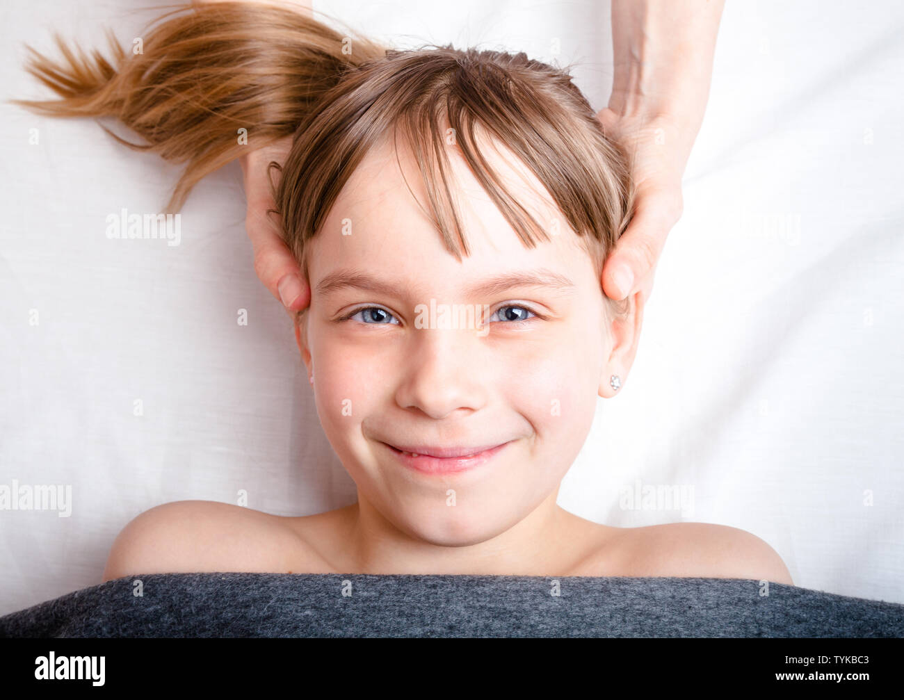 Elementary age girl's head being manipulated by osteopathic or chiropractic manual therapist in a pediatric clinic Stock Photo