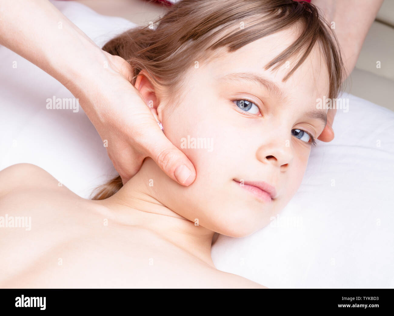 Elementary age girl's neck being manipulated by osteopathic or chiropractic manual therapist in a pediatric clinic Stock Photo