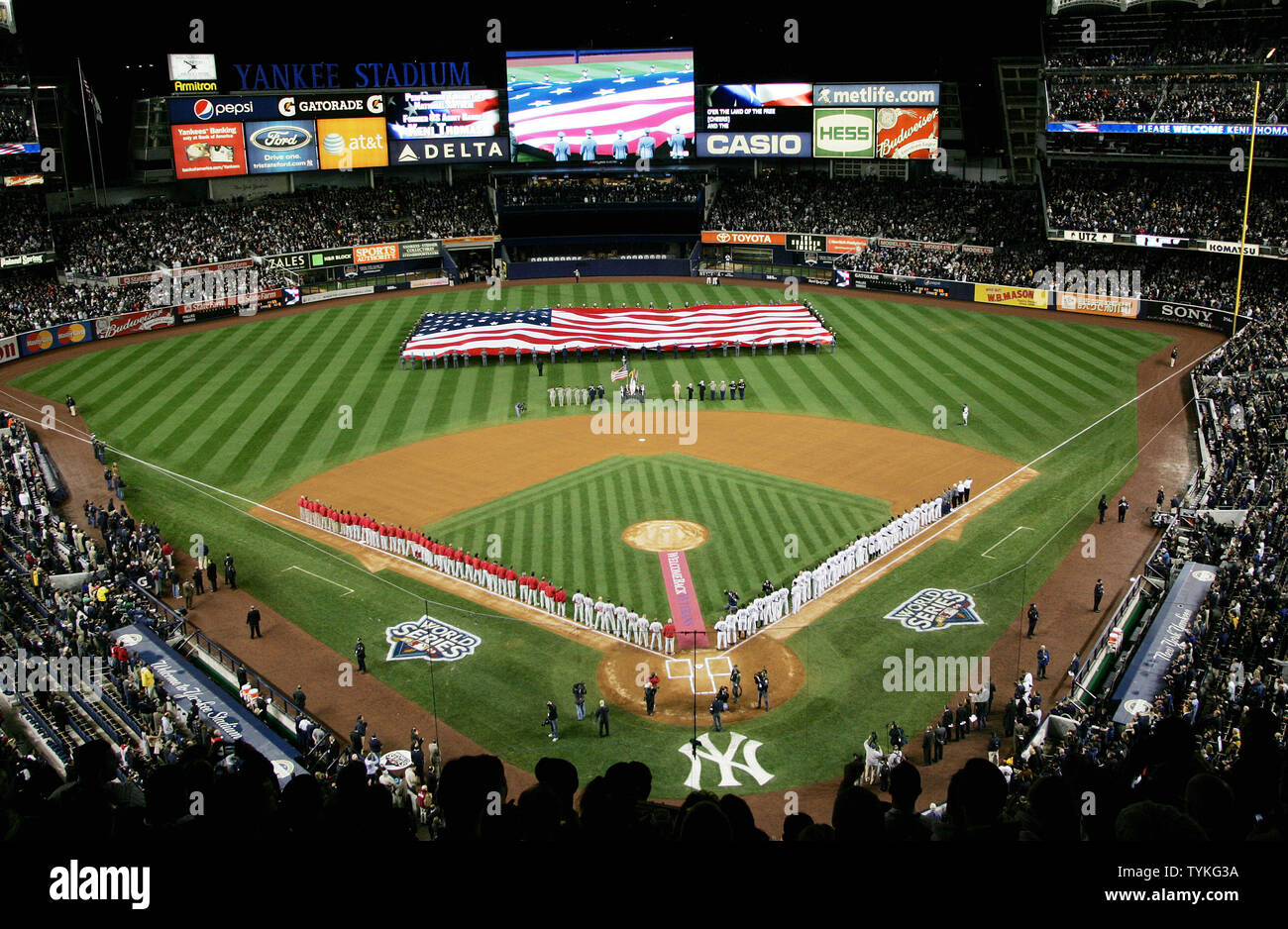 A giant American flag is displayed in the outfield as players line up
