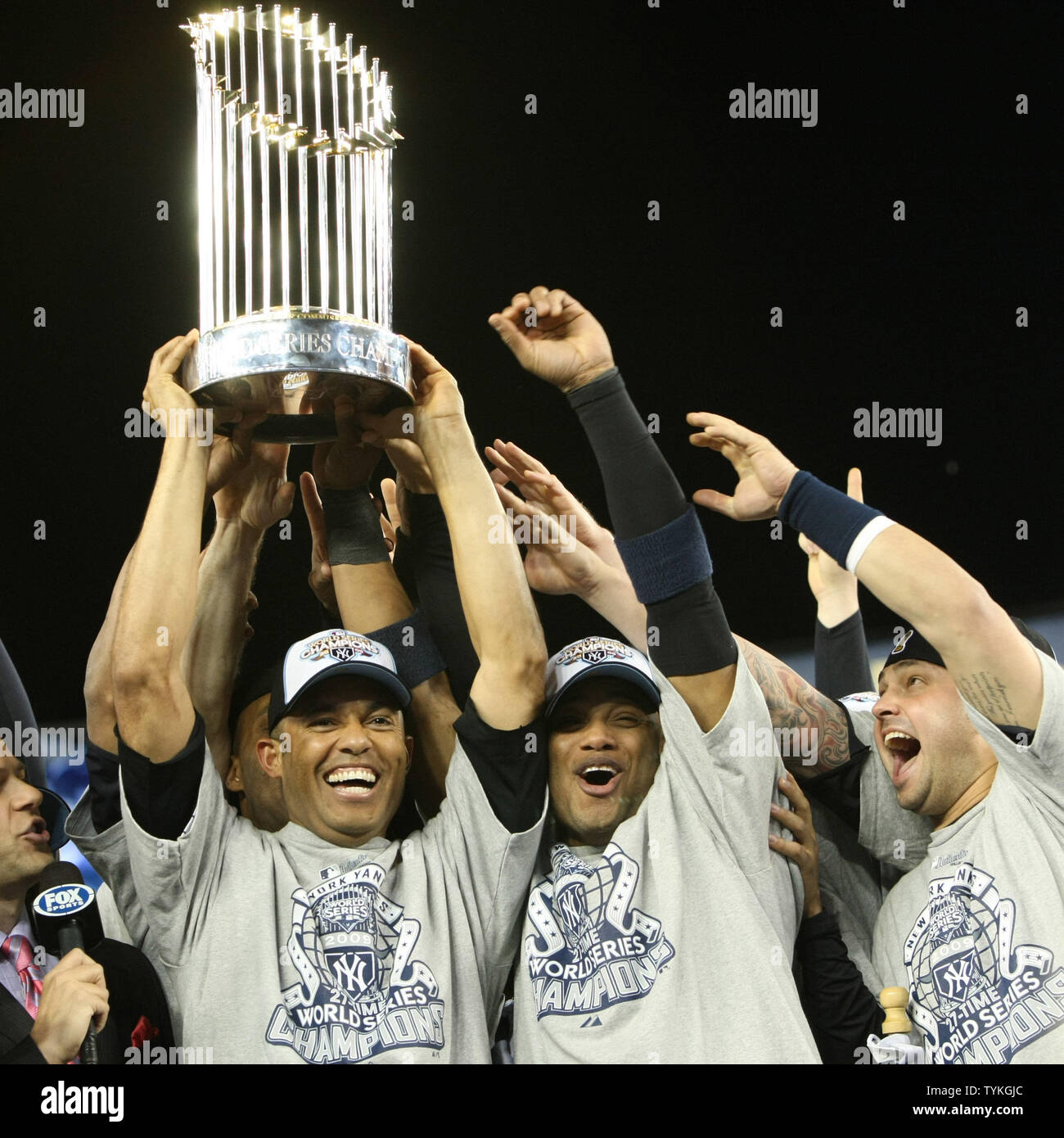 Mariano Rivera (L), hoists the championship trophy as Melky Cabrera,  center, and Nick Swisher of the New York Yankees celebrate their World  Series win after defeating the Philadelphia Phillies in game six