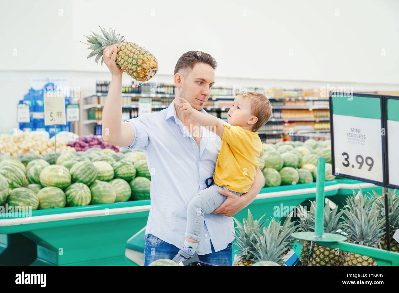 Caucasian father dad in grocery store holding pineapple and carrying