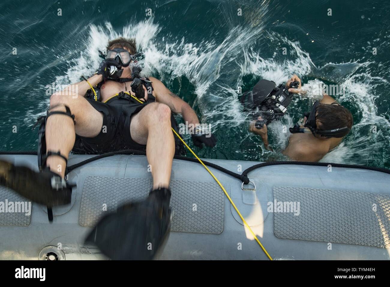 Petty Officer 1st Class Chris Liberto (left), assigned to Explosive Ordinance Disposal Mobile Unit (EODMU) 1 and Petty Officer 2nd Class Tyler Thompson from Expeditionary Combat Camera enter the water from an 11-meter ridged-hull inflatable boat during UK/US Mine Countermeasures Exercise 2017 (UK/US MCM-Ex 17) Nov. 15, 2016. The exercise is a bilateral mine countermeasures (MCM) exercise between the U.S. Navy and Royal Navy designed to provide an opportunity for both nations to share knowledge of MCM techniques to respond to mine threats. The combined MCM force will enhance MCM capabilities in Stock Photo