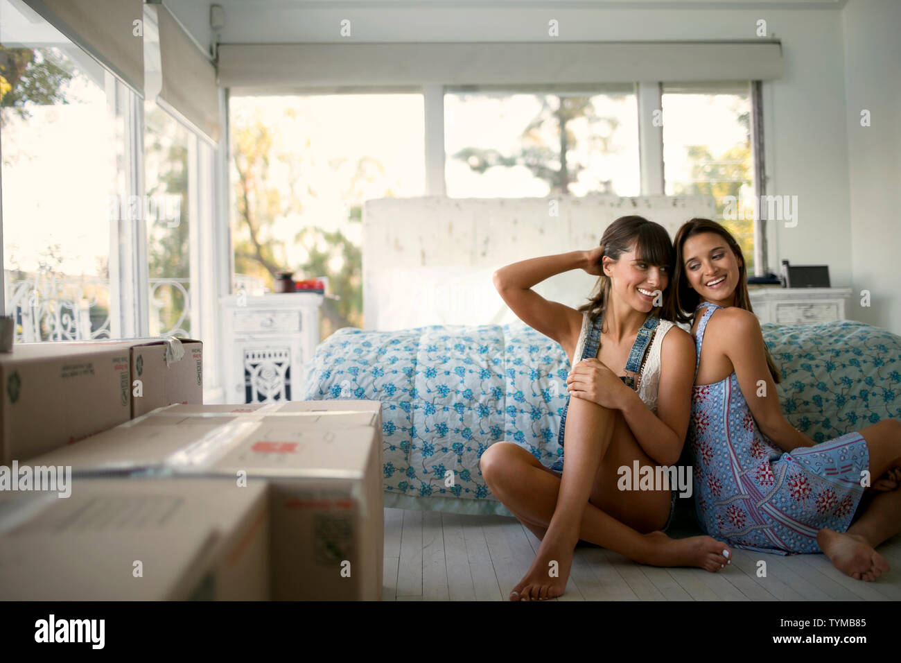 Two friends sitting on bedroom floor Stock Photo