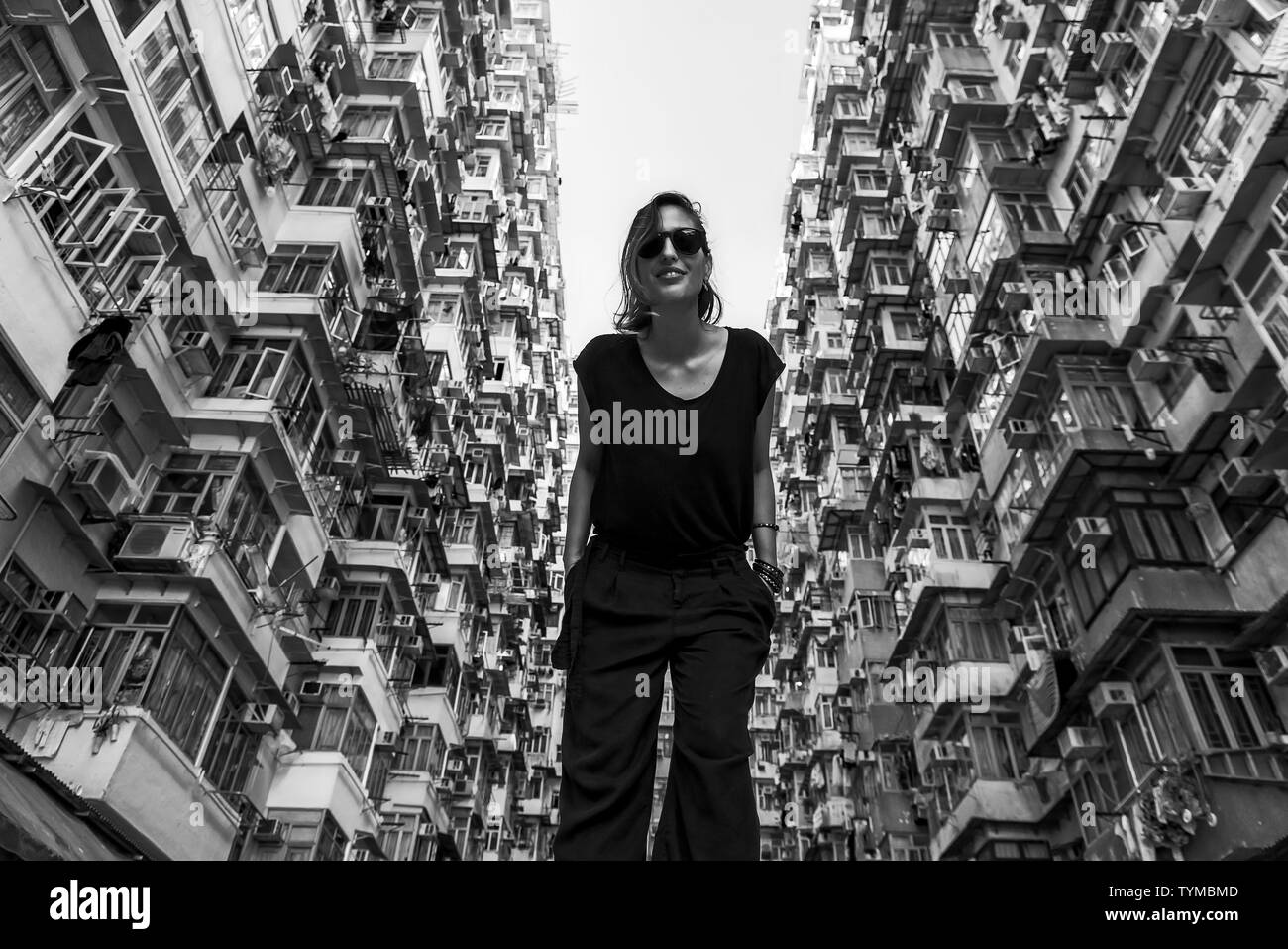 Woman in front of high-rise building with many units in Hong Kong Stock Photo