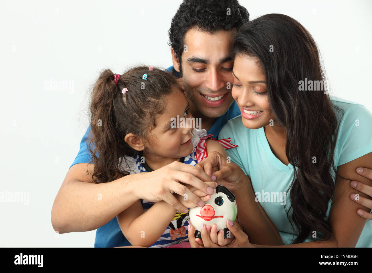 Girl putting coin into a piggy bank with her parents Stock Photo - Alamy