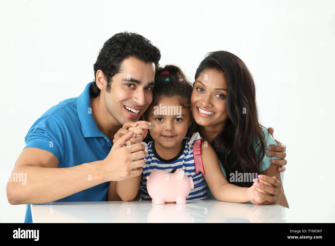 Girl putting coin into a piggy bank with her parents Stock Photo - Alamy