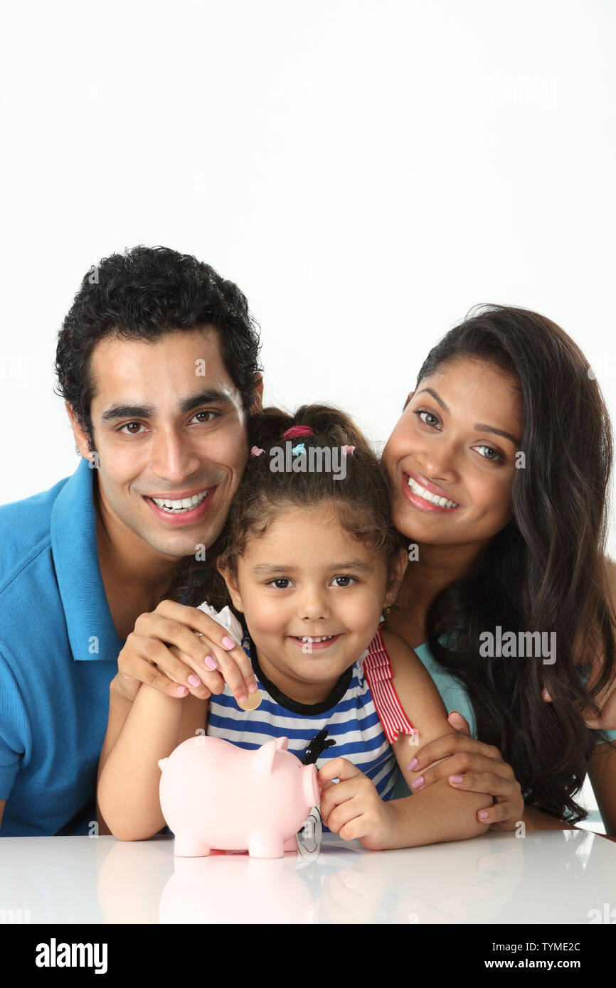Girl putting coin into a piggy bank with her parents Stock Photo - Alamy