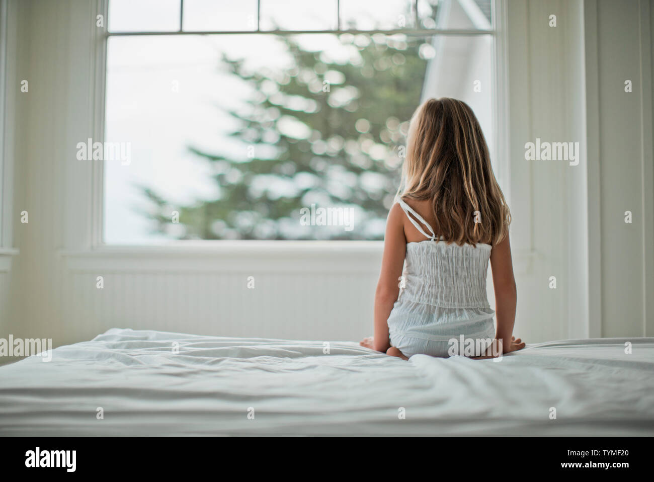 Young girl sitting on a bed. Stock Photo