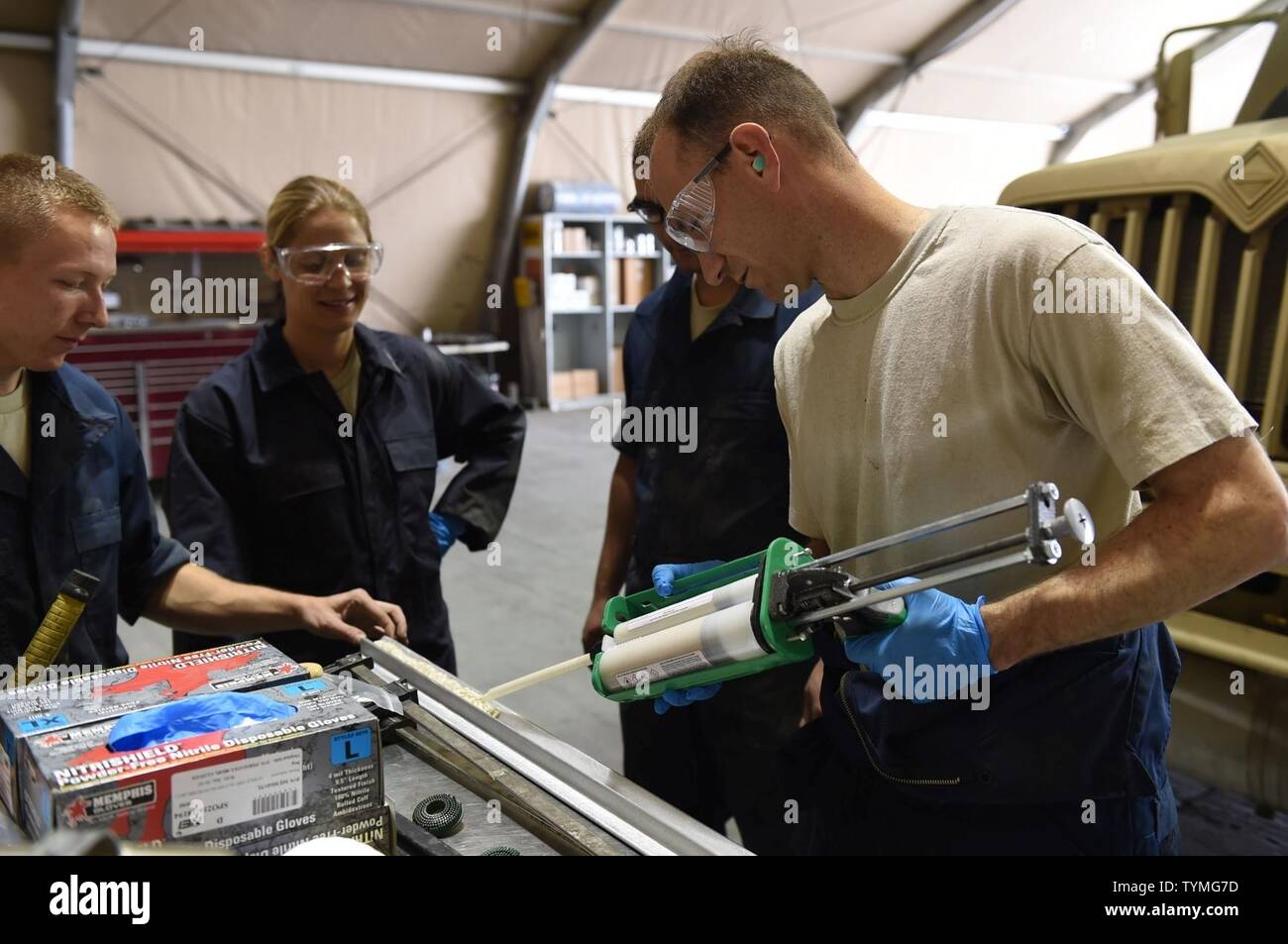 Staff Sgt. Andrew, 380th Fire and Refueler Maintenance vehicle maintainer, supports an angle beam while Col. Kevin Eastland, 380th Air Expeditionary Wing vice commander, applies an industrial acrylic adhesive for mounting the beam to an R-11 fuel truck at an undisclosed location in Southwest Asia, November 16, 2016. The angle beam is part of a service kit to strengthen the edges of the R-11 tank sump, requiring the paint to be stripped in order to create a proper bond between the beam and tank. Stock Photo