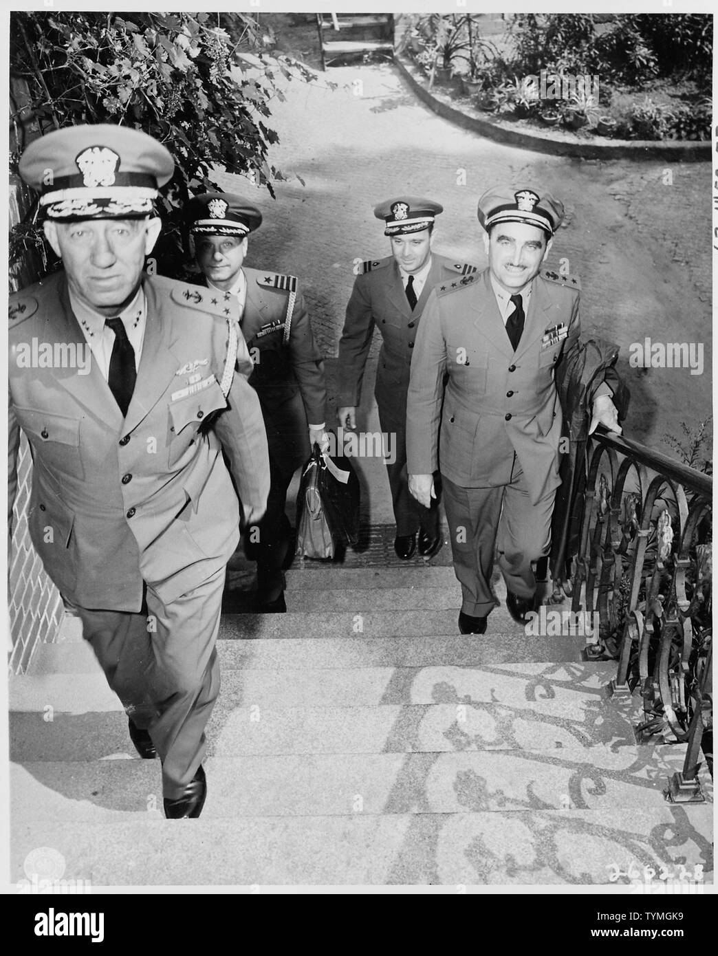 The staff officers of Fleet Admiral Ernest J. King, U. S. Navy, ascend steps to their quarters near the Little White House (residence of President Harry S. Truman during the Potsdam Conference) in Babelsburg, Germany. Left front, Vice Admiral G. M. Cooke, Jr. Chief of Staff for Cominch; right front, Rear Admiral H. L. Naples of the Military Mission to Moscow; left rear, Captain A. S. McDill, aide-de-camp to Cominch; and right rear, Commander E. J. Gough, Medical Corps, U. S. Naval Reserve. Stock Photo
