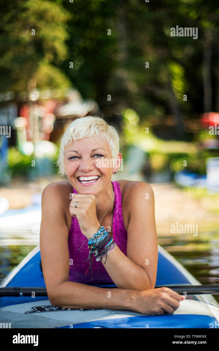 Mid adult woman prepares for paddleboarding. Stock Photo