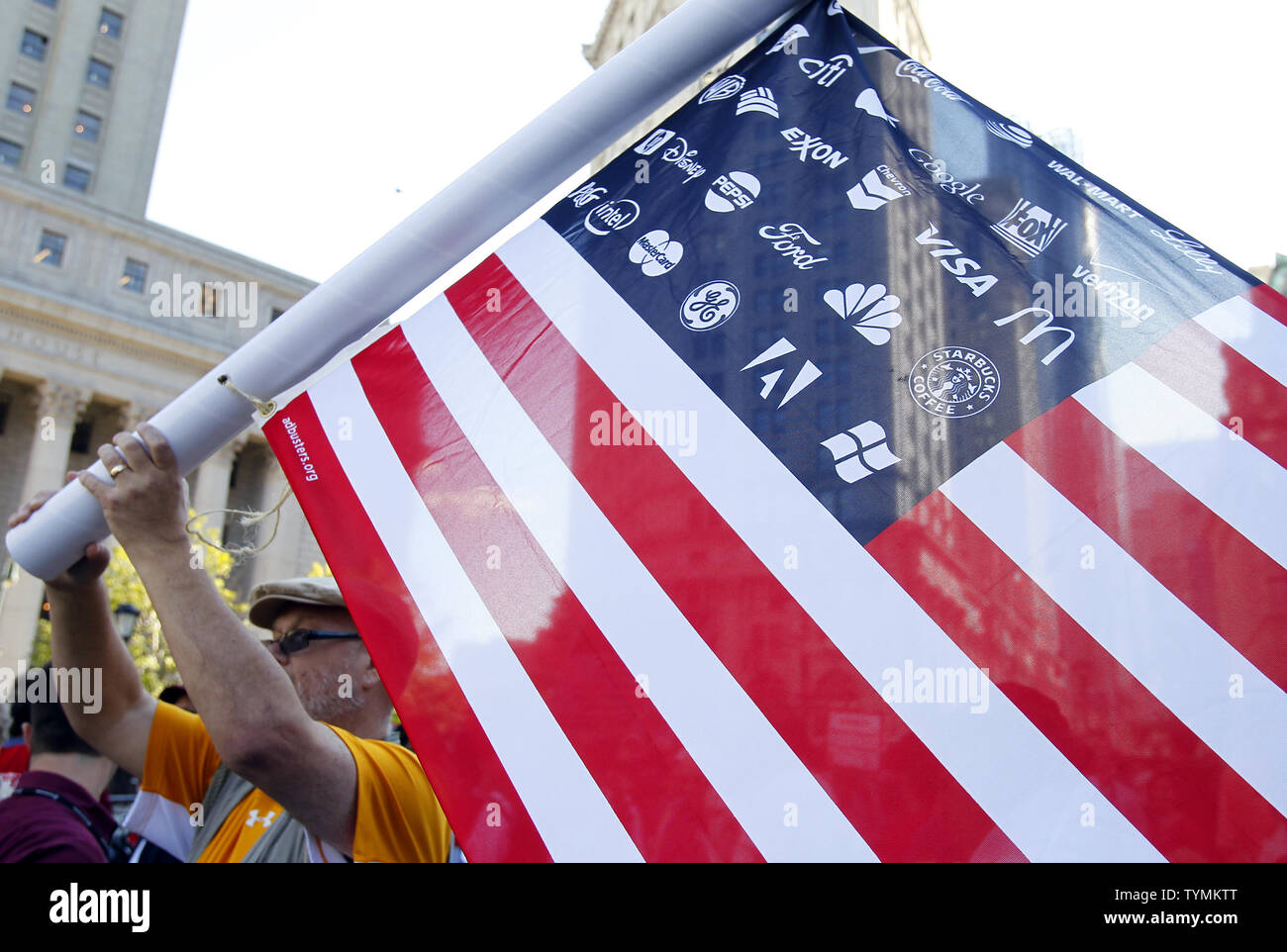 An Occupy Wall Street Protestor holds up a flag where the stars have been replaced with Corporate Brand Logos as the protestors rally around Foley Square in Lower Manhattan's financial district In New York City on October 5,  2011.     UPI/John Angelillo Stock Photo